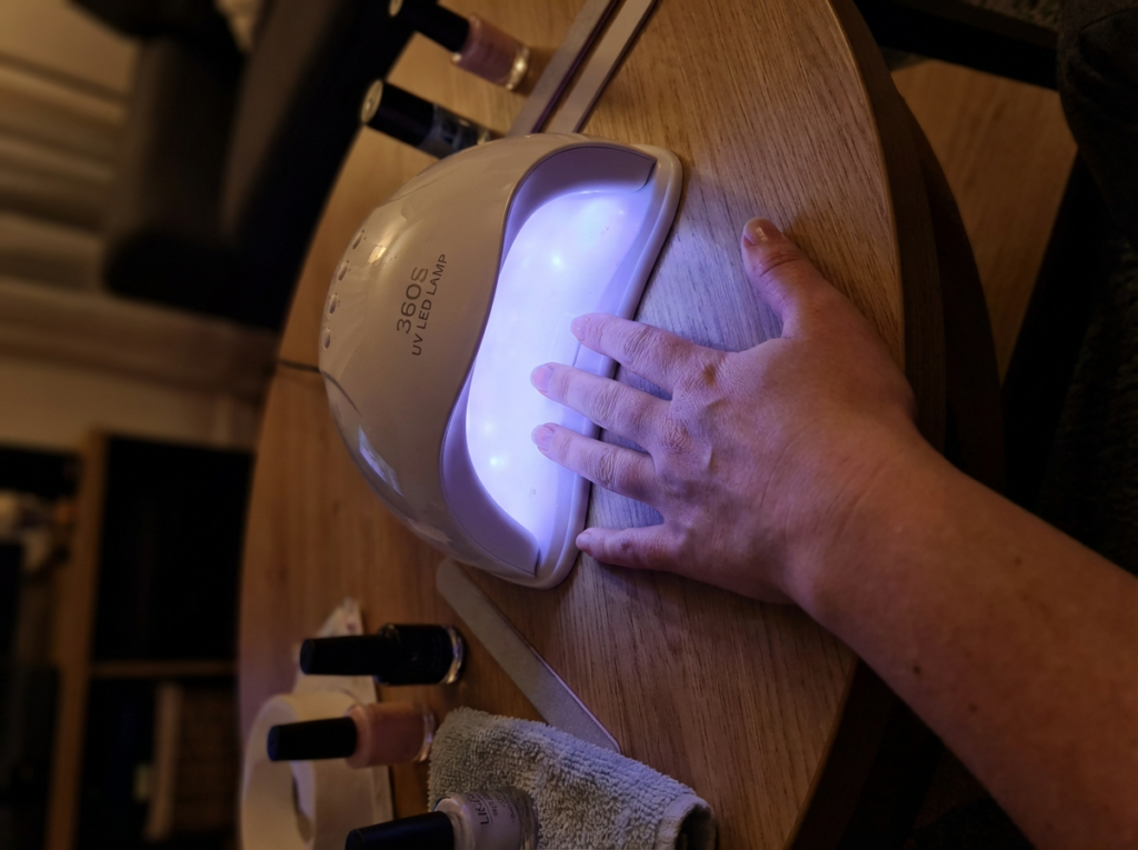 mano mal posicionada dentro de lámpara LED para uñas con curado incorrecto