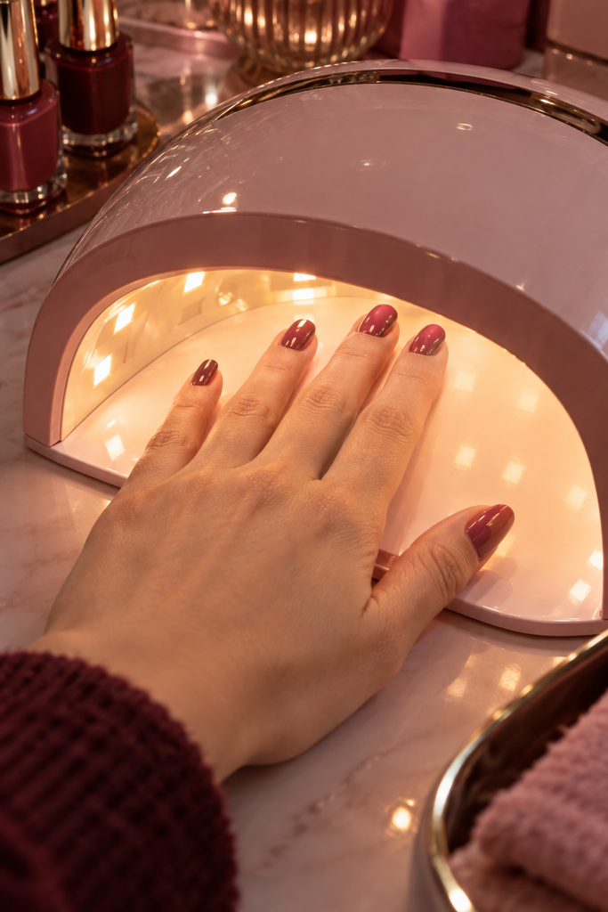 Mano bajo lámpara de uñas mostrando el pulgar en ángulo distinto al resto de los dedos